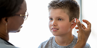a nurse placing a bone anchored hearing aid in a child's ear